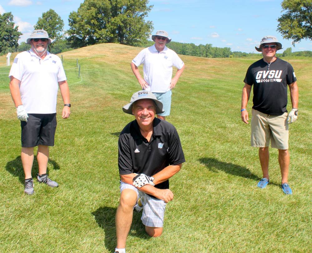 four alumni posing together after golfing